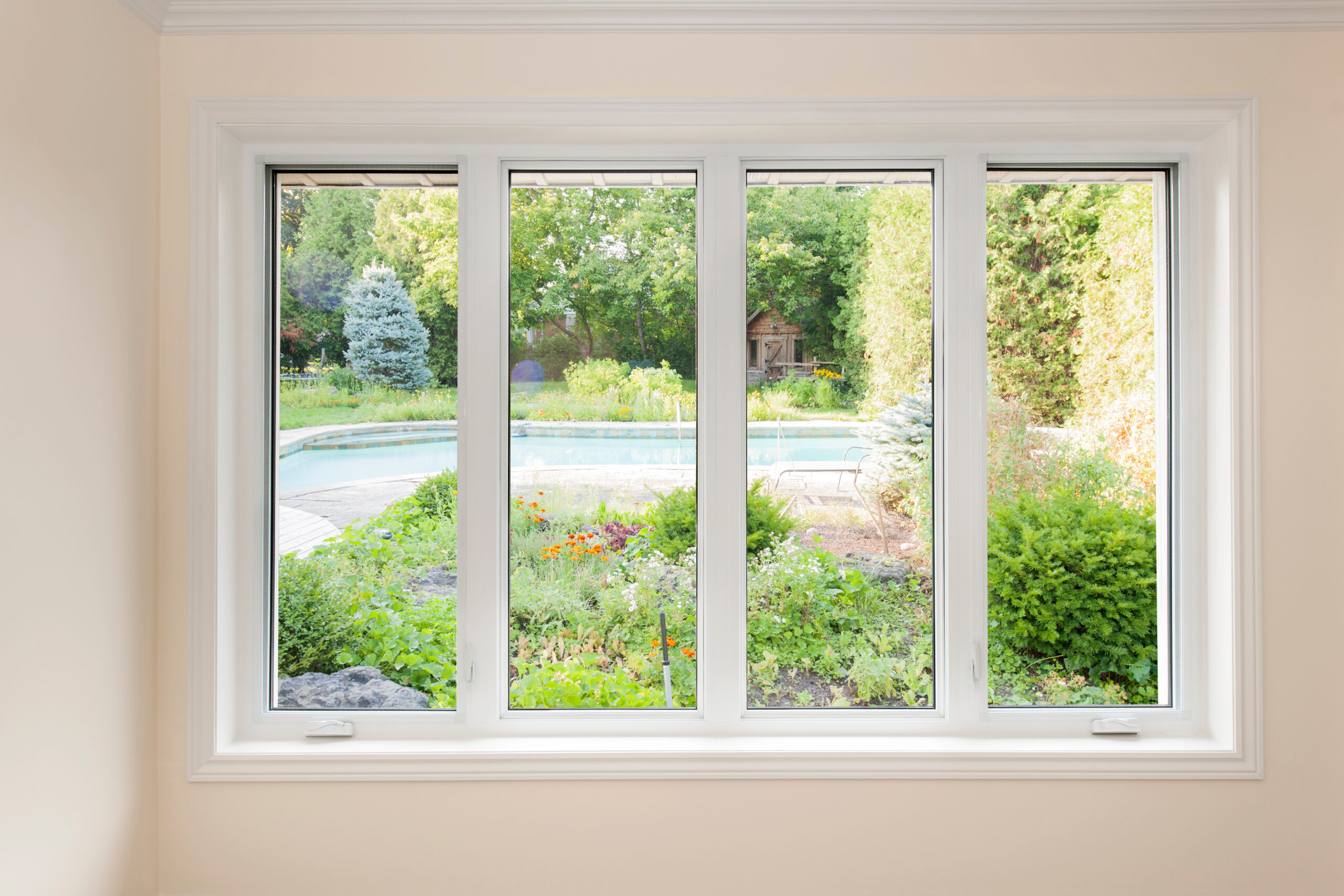 Large four pane window looking on summer backyard with pool and garden